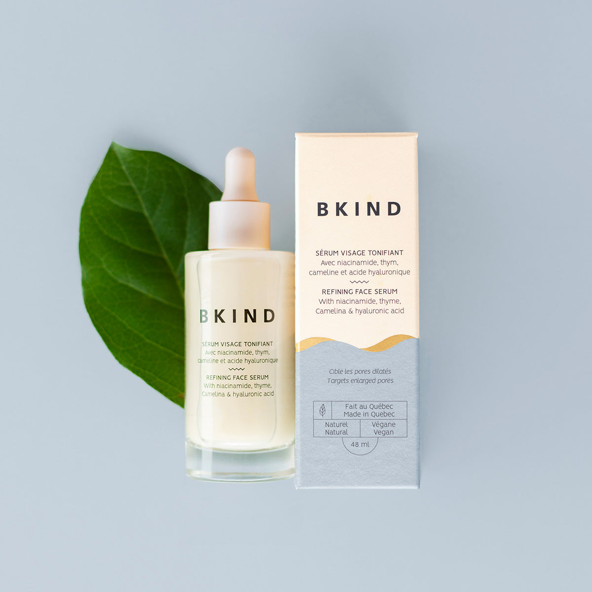 BKIND serum bottle and packaging on a light gray background with a green leaf.