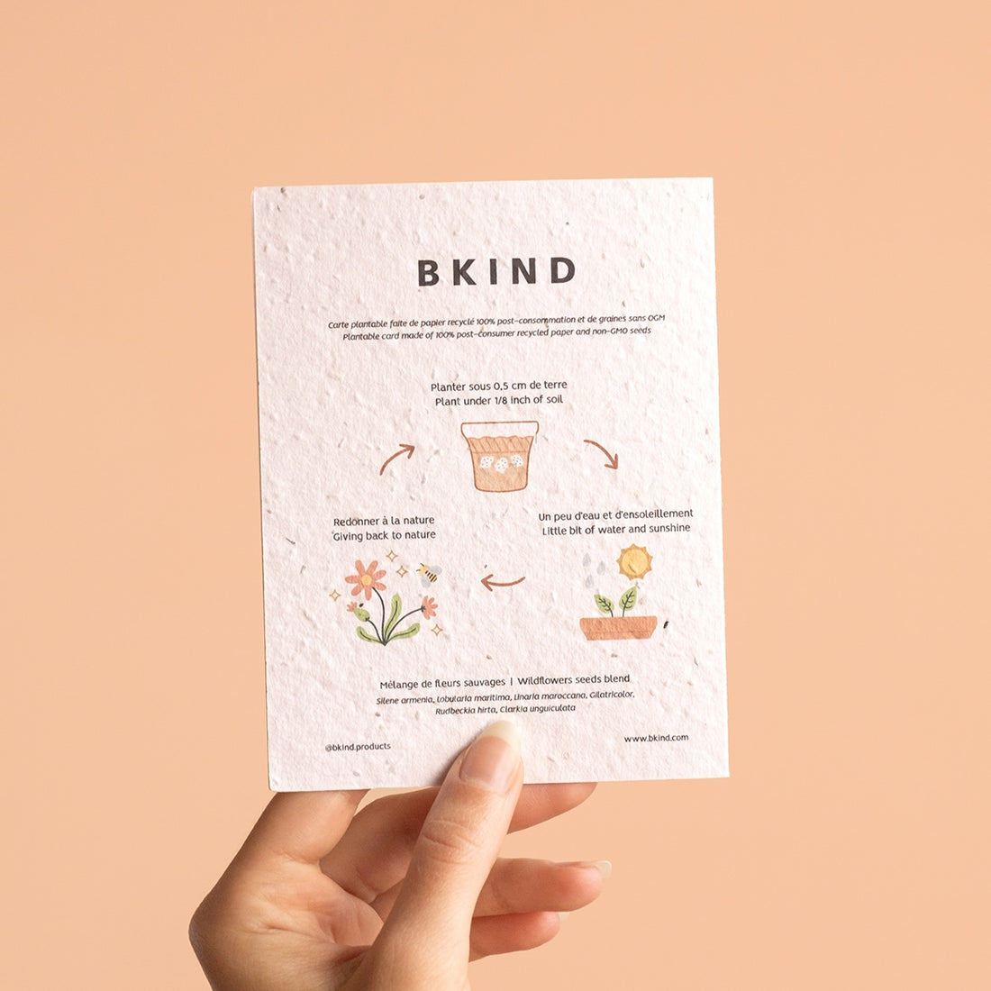 Hand holding a BKIND seed paper card against a beige background
