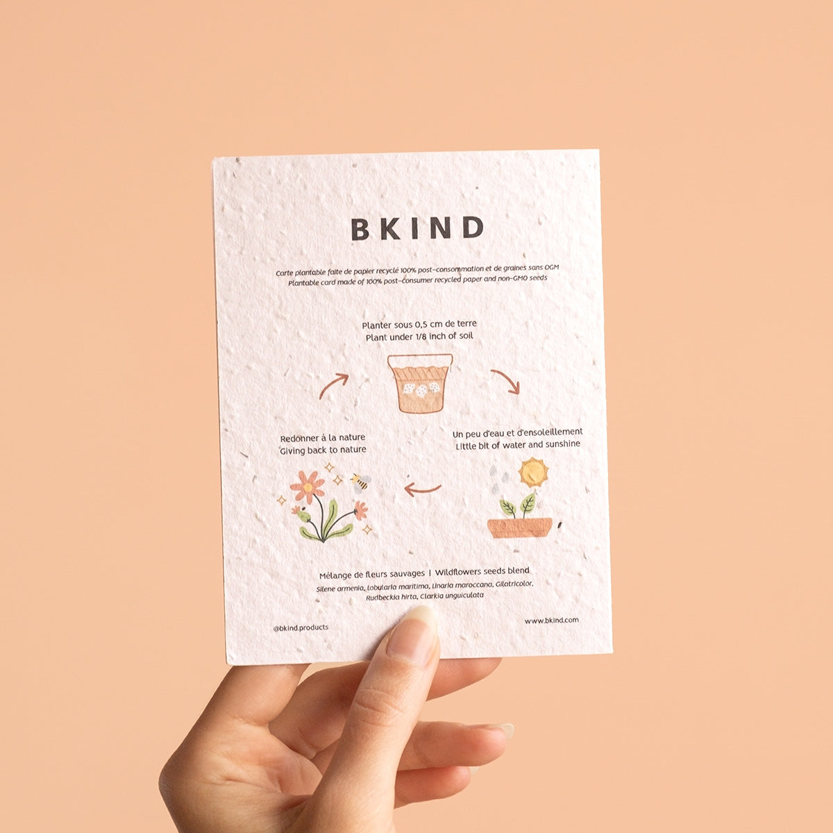 Hand holding a BKIND seed paper card against a beige background