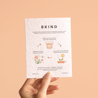 Hand holding a BKIND seed paper card against a beige background