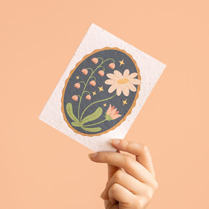 Hand holding a decorative paper with floral design on a beige background