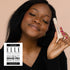Woman holding a skincare product with an &