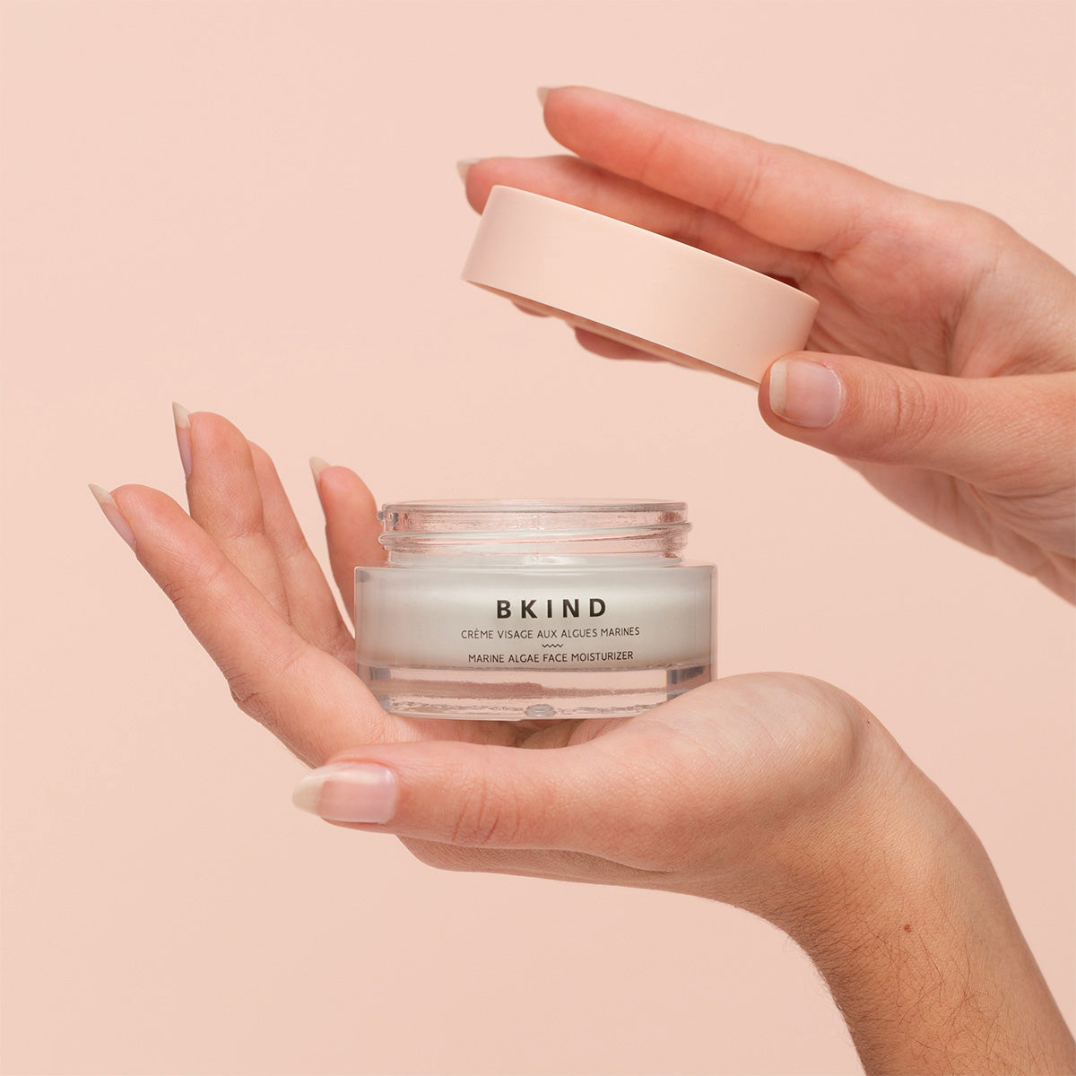 Hands holding the Marine Algae Face Moisturizer on peach background