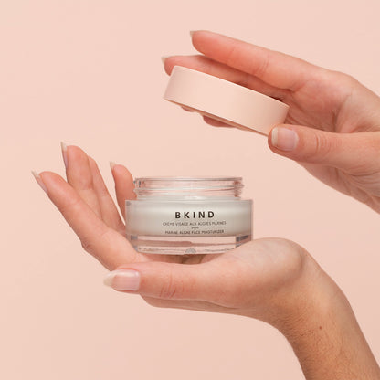Hands holding the Marine Algae Face Moisturizer on peach background